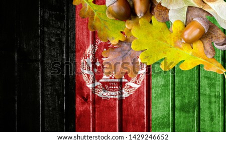 Afghanistan flag on autumn wooden background with leaves and good place for your text.