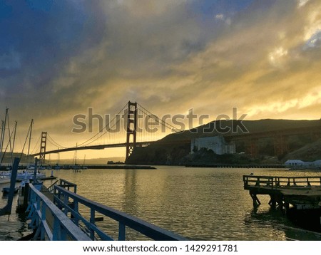 yellow, orange, and red colors on the sky, with some clouds that give this epic photography with close up from port and pier.