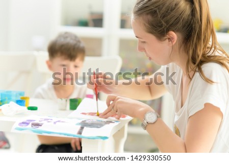 Educator teaching a little boy at painting hour