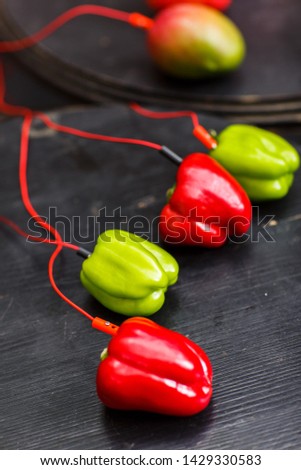 Photo of red and green pepper, avocado with red wires on black table