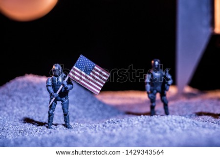 selective focus of toy astronauts holding american flag in space 