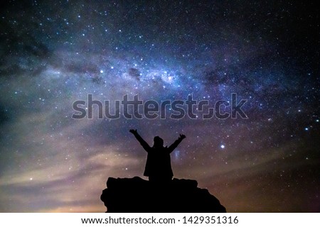 A woman sits on a rock staring deep into the vast universe philosophically reminding oneself of our small place in the cosmos Royalty-Free Stock Photo #1429351316