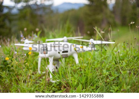 
The white drone lies on the green grass in the mountains