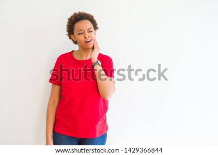 Young beautiful african american woman over white background touching mouth with hand with painful expression because of toothache or dental illness on teeth. Dentist concept.