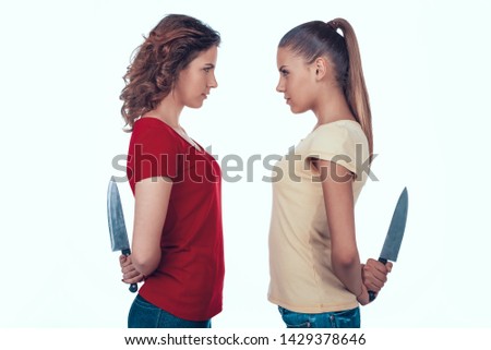 Aggressive Jealous Women Fighting. Girls Hide Knives behind Back. Enemies Going to Kill Concept Photo on White Background. Royalty-Free Stock Photo #1429378646
