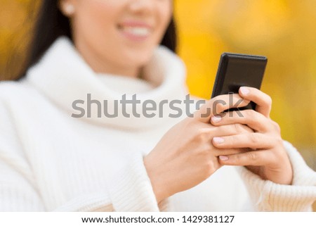 season, technology and people concept - beautiful young happy woman using smartphone or taking selfie in autumn park
