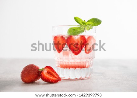 Fresh lemonade with ice, mint and strawberry in glass on white table background. Cold refreshing summer drink. Sparkling glasses with berry cocktail. Copy space for text