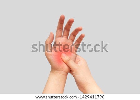 Young female suffering from pain in hands and massaging her painful hands isolated gray background. Causes of hurt include carpal tunnel syndrome, fractures, arthritis or peripheral neuropathy.
