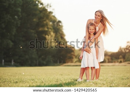 Portrait of positive people. Mother and daughter enjoying weekend together by walking outdoors in the field. Beautiful nature.