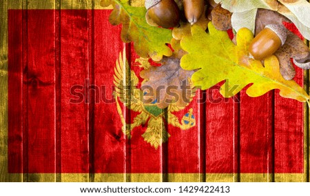 Montenegro flag on autumn wooden background with leaves and good place for your text.
