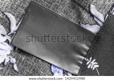 Blank black clothes label on textile background closeup