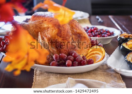 Family dining room table set with roast stuffed turkey for Thanksgiving Day. Selective focus on turkey with blurred background..