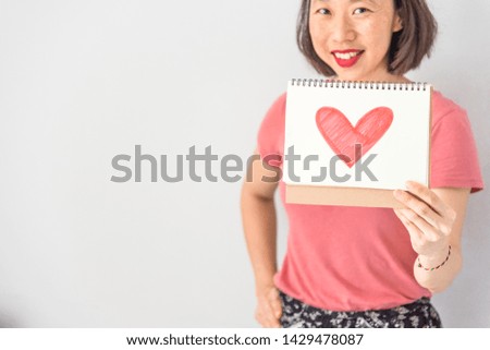 Close up of smiling woman hand holding heart shape card. Love and relationship concept.