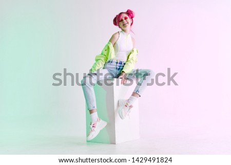 woman with pink hair is smiling sitting on a cube
