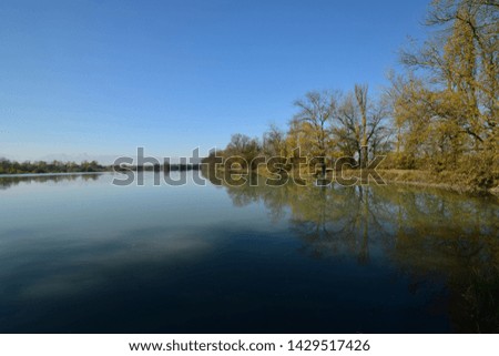   Panorama of an autumn evening lake with blue water and trees with yellow leaves on the shore against the blue sky in the foothills of the North Caucasus                             