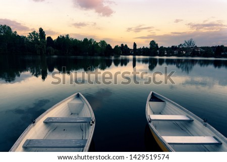 wooden boats on a calm lake called Csonakazo Lake in Szombathely Hungary at dusk after sunset