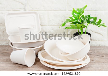 Eco friendly biodegradable paper dishes and glass on wooden background. Royalty-Free Stock Photo #1429531892