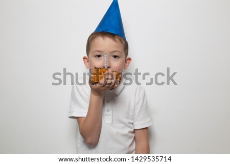 horizontal portrait child boy in a cap holding a cake with candles in a white t-shirt on a white background, the concept of the holiday children's birthday