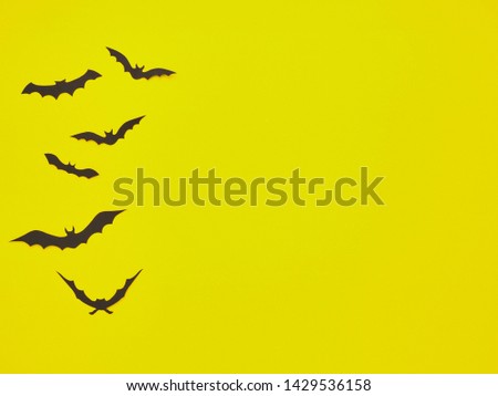 Halloween holiday concept. Black bats on yellow background. Top view, flat lay
