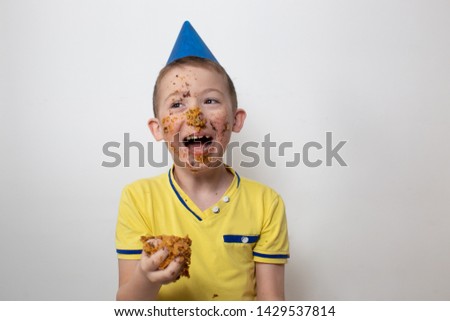 horizontal portrait child boy in a cap and in a yellow T-shirt soiled in a cake on a white background, the concept of the holiday children's birthday