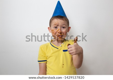 horizontal portrait child boy in a cap and in a yellow T-shirt soiled in a cake on a white background, the concept of the holiday children's birthday