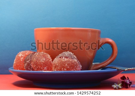 Red-blue mug with tea, two-color marmalade, lavender flower on a blue background