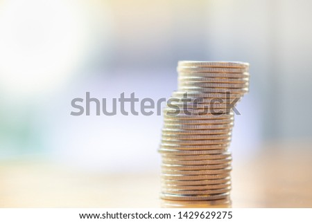 Money, Finance and Risk concept. Close up of unstable stack of silver coins on wooden table with copy space.