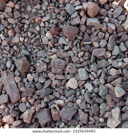 Macro photo of crushed stone and gravel on the ground. Texture background brown  stones on a black earth background. Image of broken stones and gravel