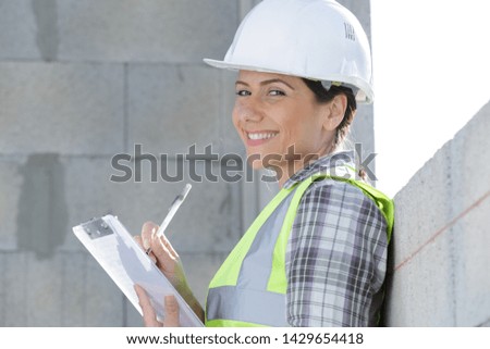 woman writing on clipboard on construction site