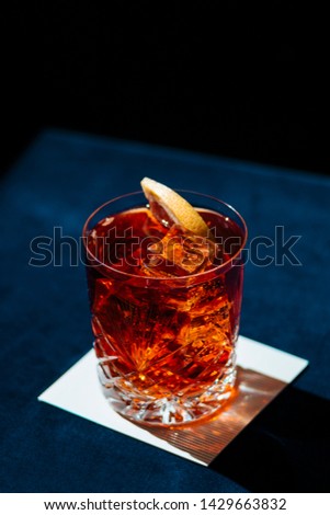 Negroni IBA cocktail, with gin, bitter, vermut, and orance slice. Colorful, and dark background. Royalty-Free Stock Photo #1429663832