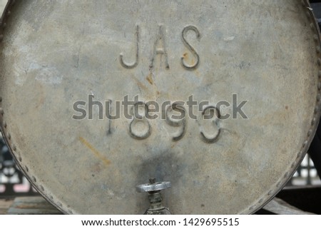Photography of the side of an old metal barrel with an aluminum valve close-up.