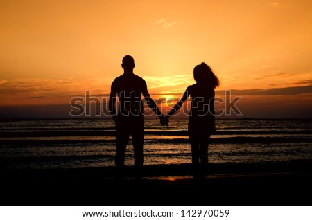 Couple enjoying their time at the sunrise on the beach, couple holding their hands in a romantic scene