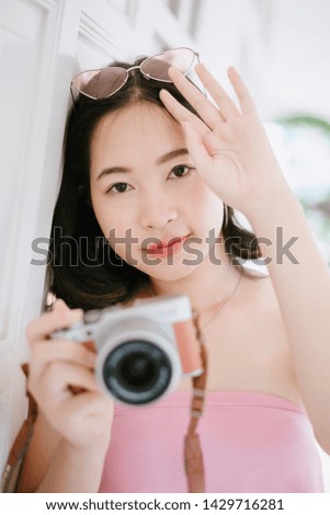 Beautiful asian woman photographer holding photo camera.