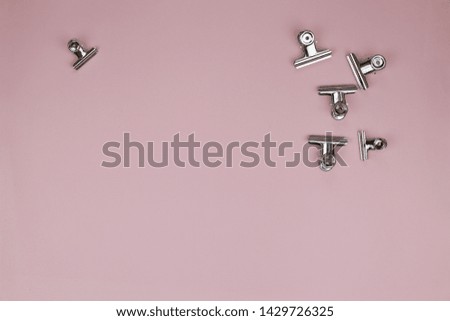 Metal stationery clothespins on a light pink background