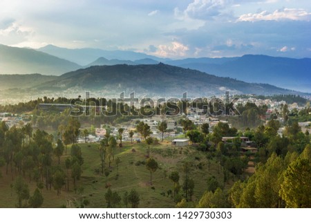 The picture showing houses and the greenry in Mansehra city with clodus and mountains 