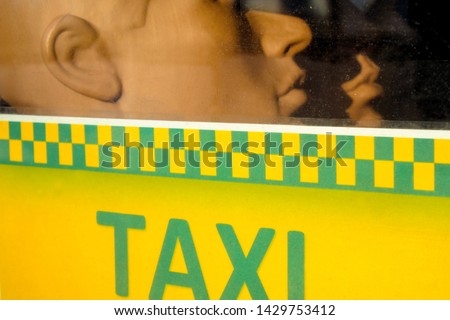 Two profiles of dummy heads over the taxi inscription. Plastic people behind the window glass. Quarantine concept.