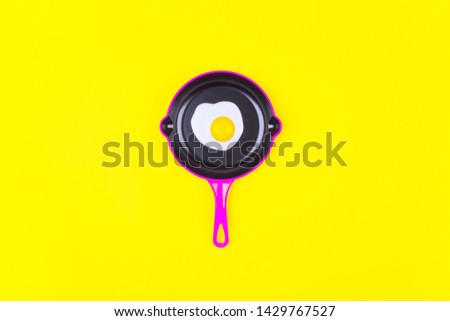 Fried eggs on pink pans over yellow background. Top view. Flat lay. Minimal style.