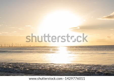 Scenic sunset over the sea. The sun sets on the water. Clouded sky is painted with bright colors. Sunset beach in a summer evening. Brazil.
