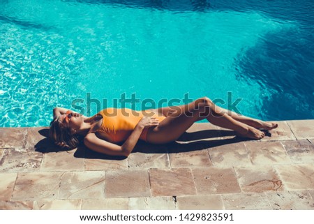 Emotional portrait of Fashion stylish portrait of pretty young hipster blonde woman posing in the swimming pool. hat, swimsuit, outdoor fashion portrait 
,going crazy,elegant black hat cool 