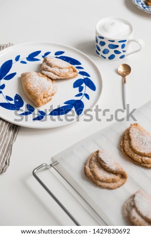 Delicious homemade dessert on blue plates. Shortbread sweet with coffee in a white mug. teaspoon golden. Saucer with earrings of leaves. On a white background.