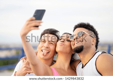 A woman and two men have fun and take photos with a smartphone.