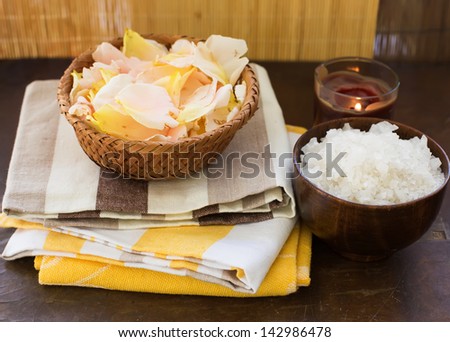Spa theme. Sea salt with candle and rose petals on wooden background. Selective focus.