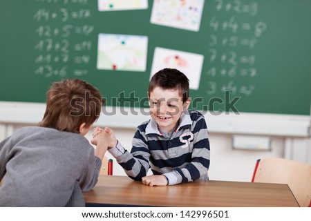 Two male students in arm-wrestling match in the classroom