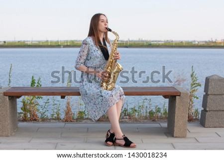 Young woman with saxophone in the park. Portrait