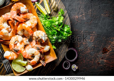 Shrimps on tray with parsley, lime slices and onion rings. On dark rustic background
