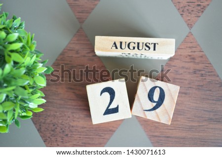 Date of August with leaf on diamond pattern table for background.