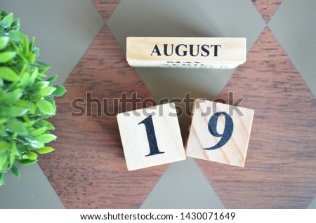 Date of August with leaf on diamond pattern table for background.
