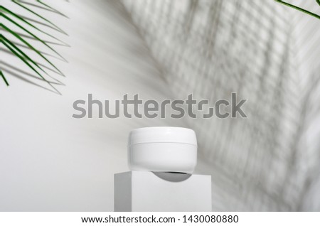 White jar of cream on a stand on a white background with tropical palm leaves and their shadow. Stylish look of the product, mock up, identity. Royalty-Free Stock Photo #1430080880