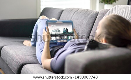 Woman choosing movie from online stream service with tablet. Watching series with on demand video (VOD) website concept. Streaming digital film from site by tv network. Mockup on smart device screen. Royalty-Free Stock Photo #1430089748