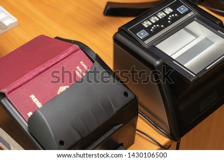 The process of scanning a German biometric passport to register the fact of crossing the state border. Male hand applies a passport to the scanning device. Concept of overseas travel Royalty-Free Stock Photo #1430106500